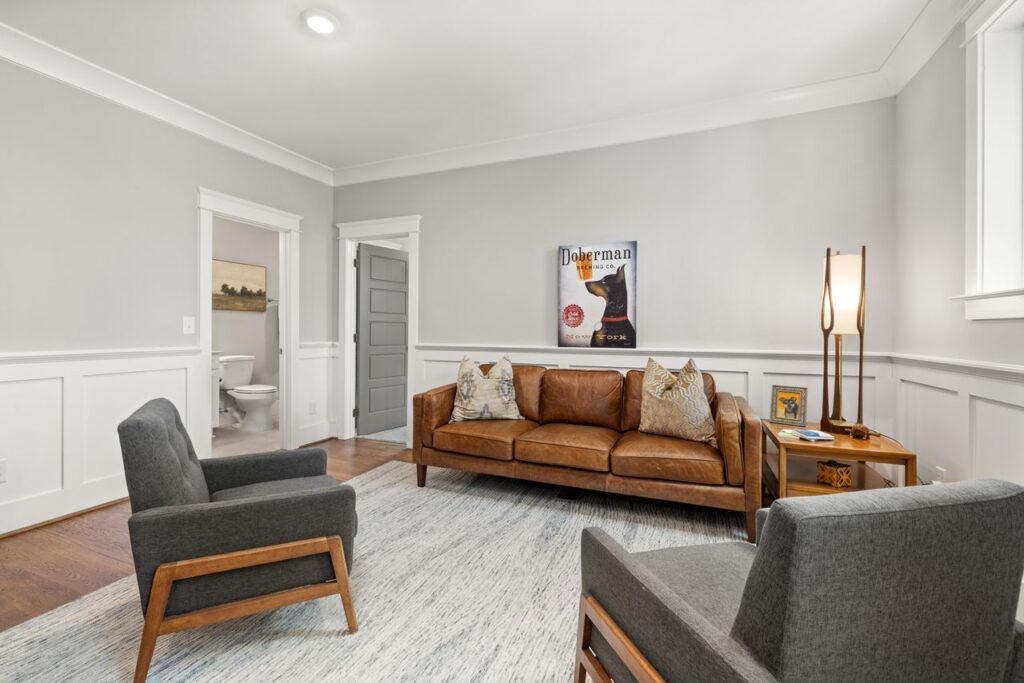Elegant modern living room with brown leather sofa and gray armchairs.